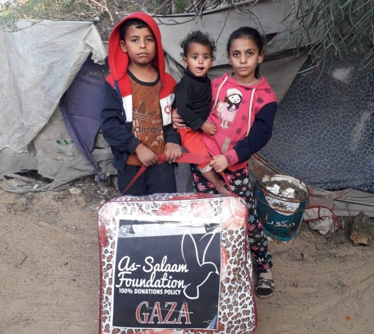 Young children in Gaza with a pack of blankets donated through a warmth project.