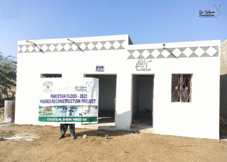 A man stood outside his new house in Pakistan which was built through a housing project after the Pakistan Floods.