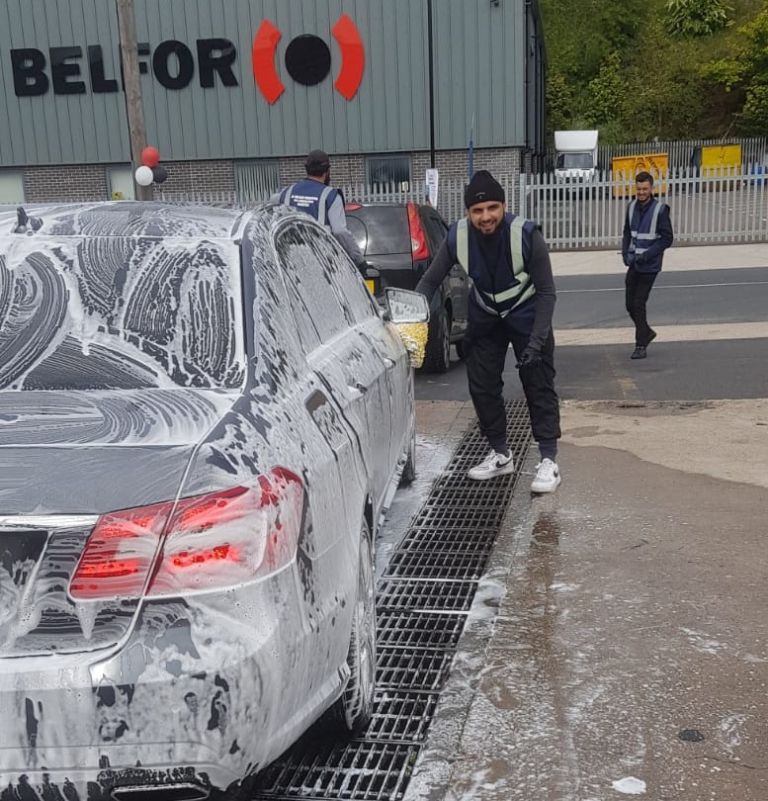 A volunteer smiling and getting involved in a charity car wash