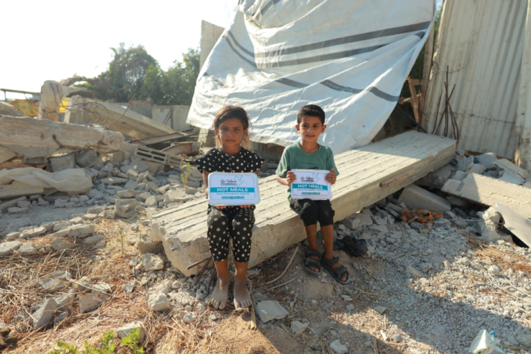 Young children holding hot meals from the feeding programmes package