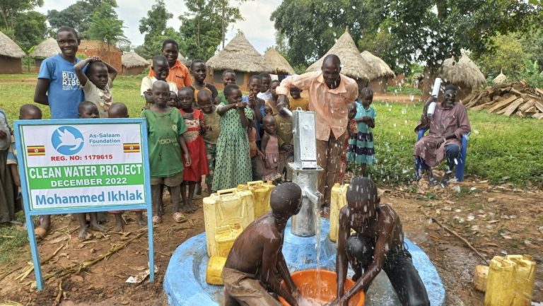 People in Africa gathered around a hand pump well installed by As-Salaam Humanitarian Foundation as part of their clean water projects.