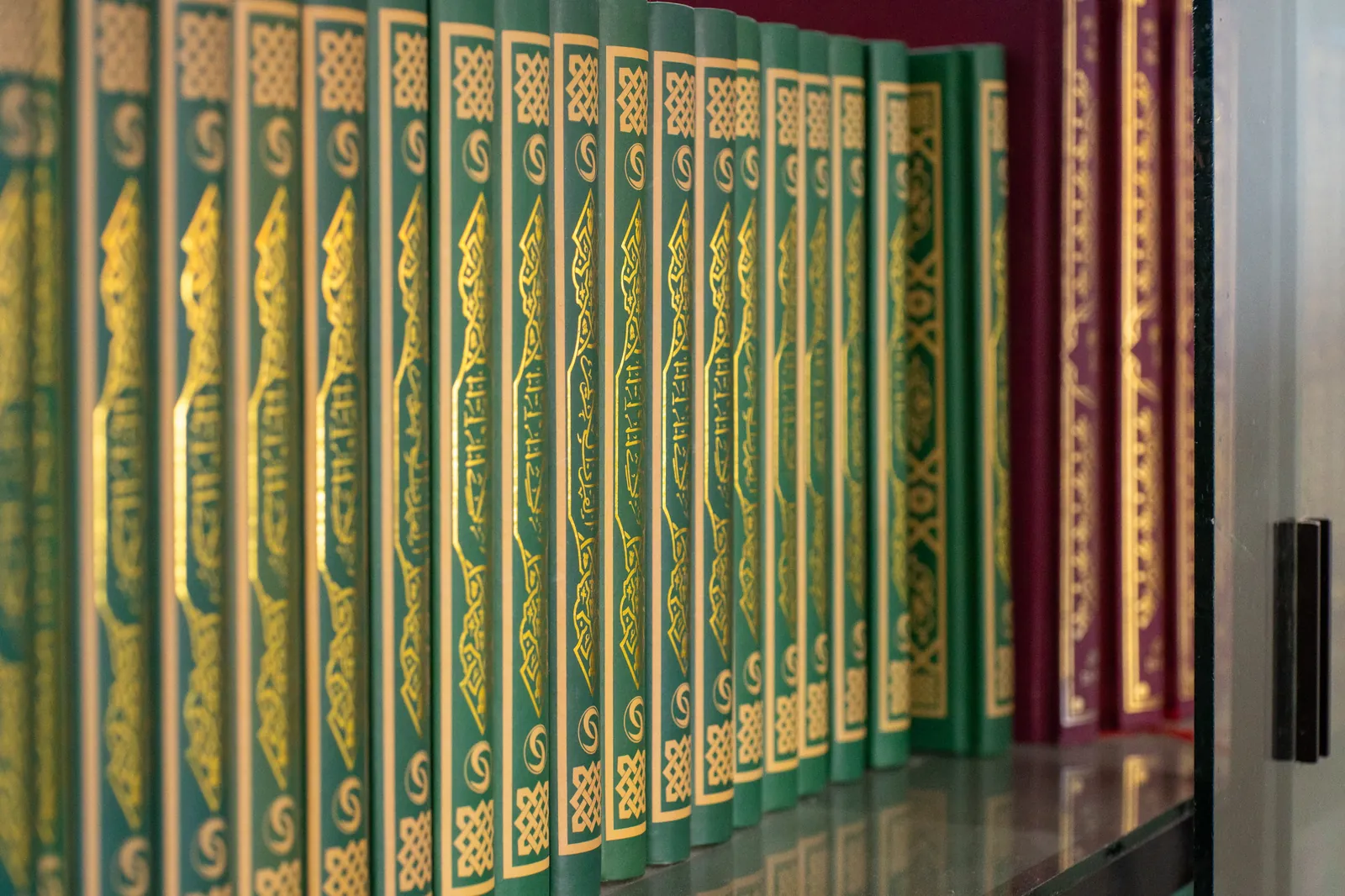 How to Pray the Janazah Prayer 2 Rows of green and gold Islamic book volumes on a mosque bookshelf